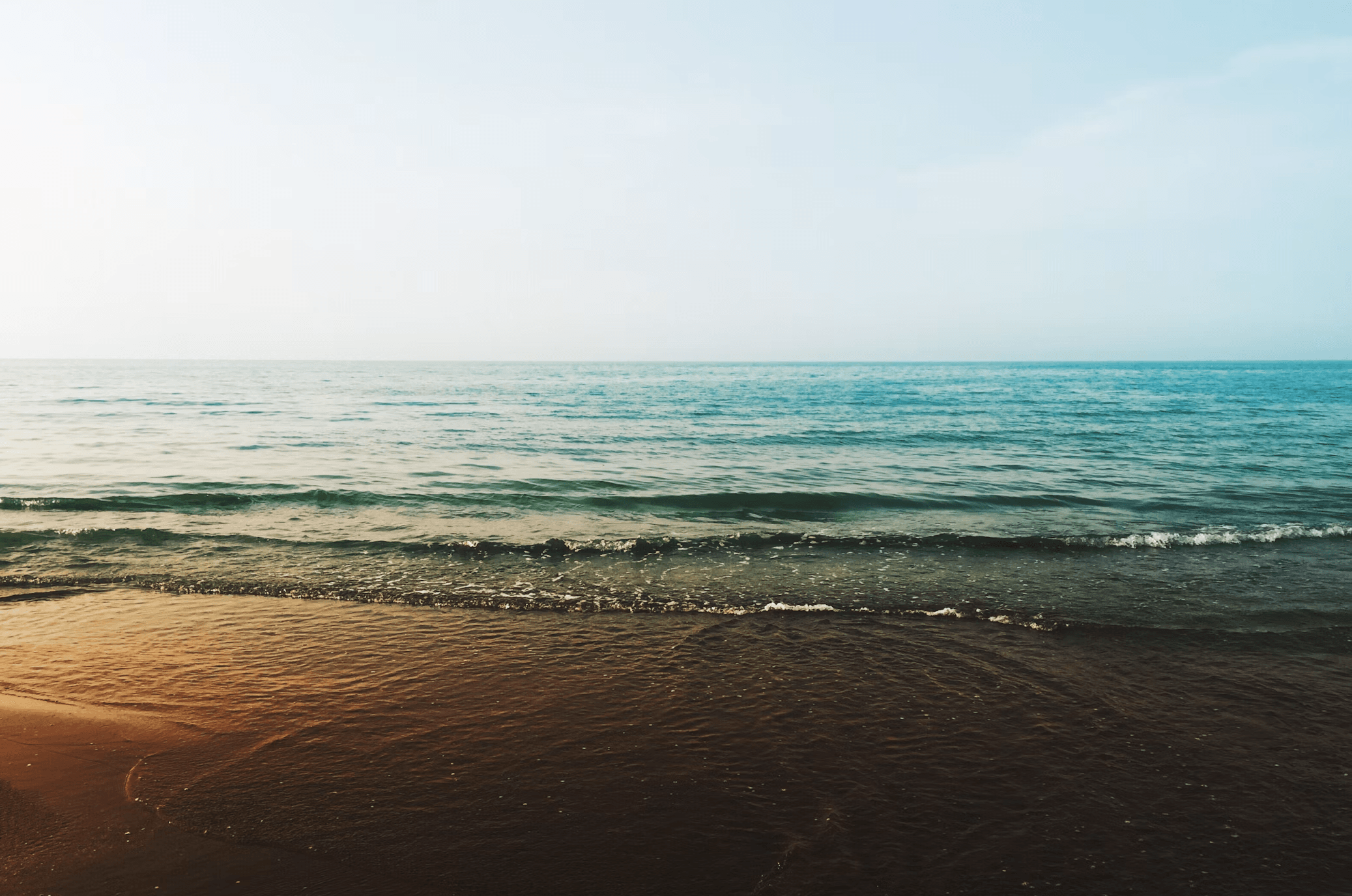 Calm ocean meeting a sandy shore at golden hour